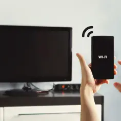 Ręce sterują telefonem z napisem WI-FI, łącząc go z telewizorem przez wifi direct.