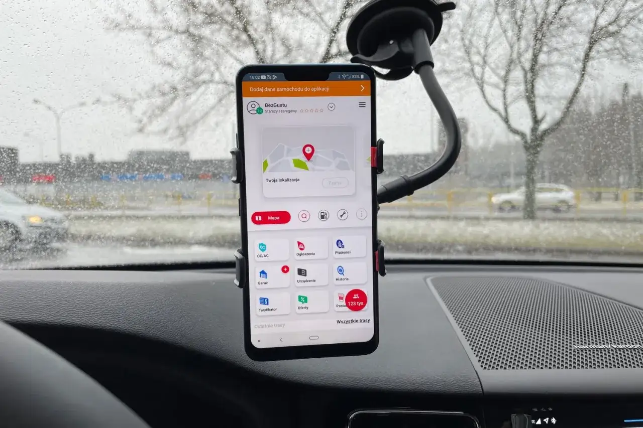 Telefon z aplikacją nawigacja Yanosik zamontowany na szybie samochodu. Widok na mapę i funkcje aplikacji.